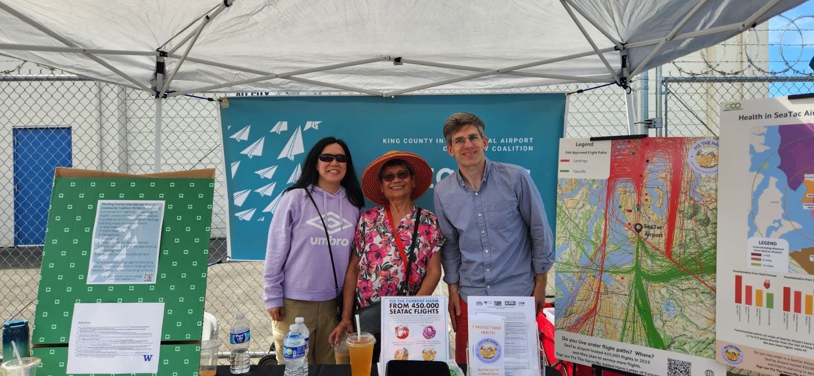 Tres activistas de la lucha contra el Aeropuerto Internacional del Condado de King en una feria local de recursos comunitarios